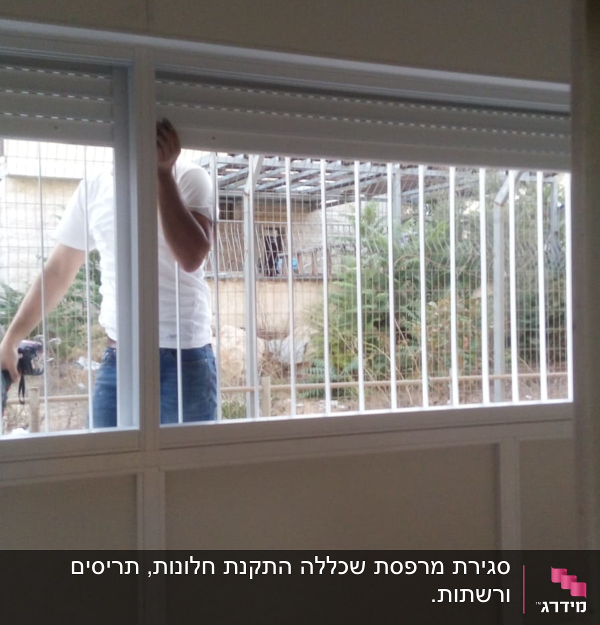 אדם מתקין תריסי אלומיניום בחלון